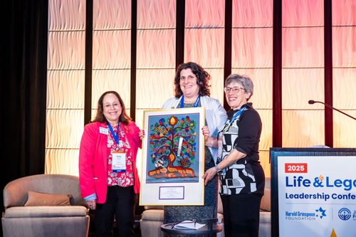 Three 2025 Life & Legacy Event Conference attendees holding up a piece of art